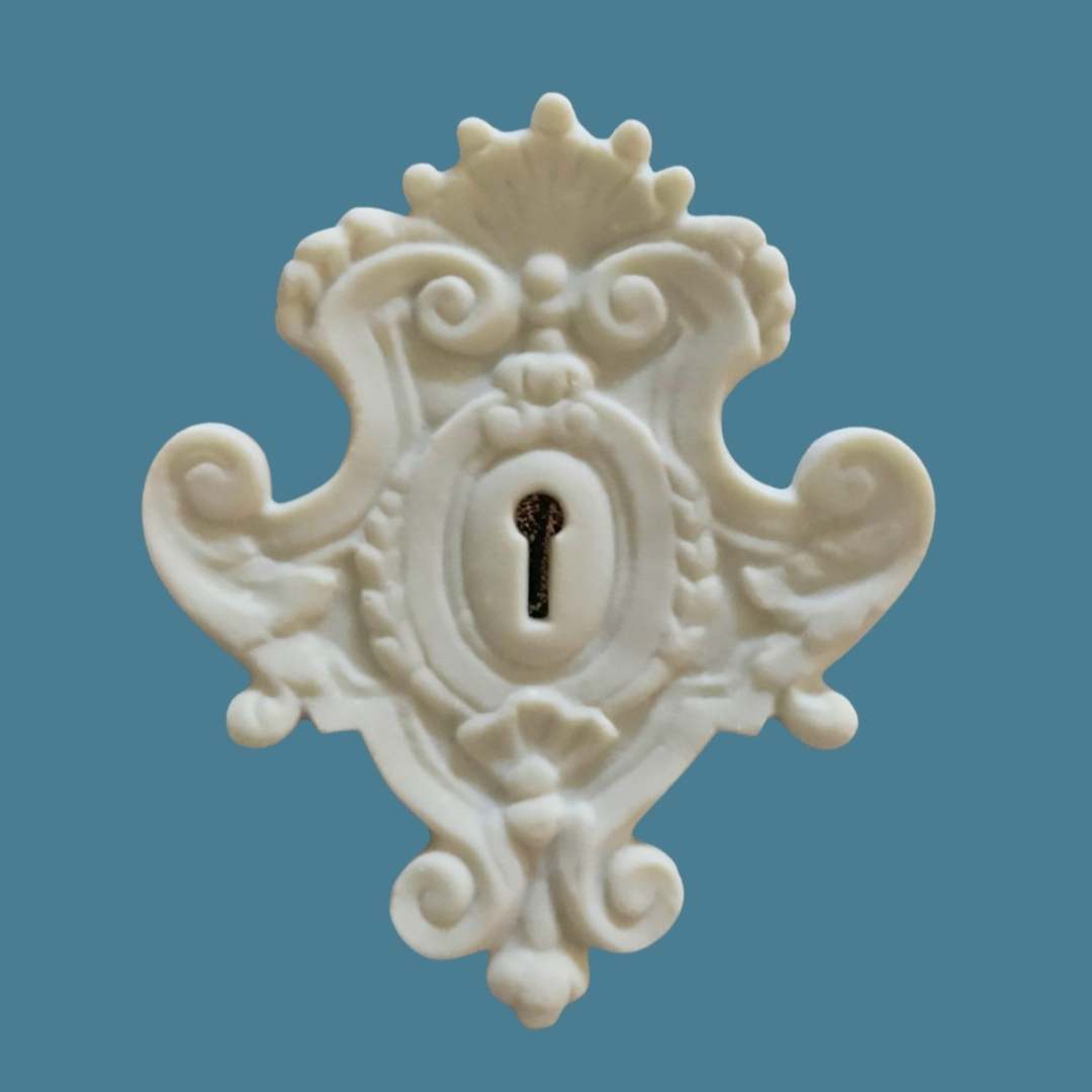 E5 Large Victorian Escutcheon, a white Efex flexible moulding keyhole surround with crown crest, shell and scrolls, shown around a brass keyhole