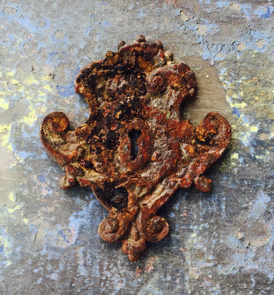 E5 Large Victorian Escutcheon Efex flexible moulding keyhole plate with scrolled edges, given a faux rusted iron finish on a distressed painted surface