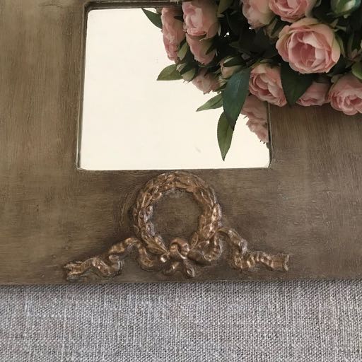 Weathered wooden mirror frame with a gold B1 wreath and bow Efex flexible moulding below the glass, reflecting pink roses