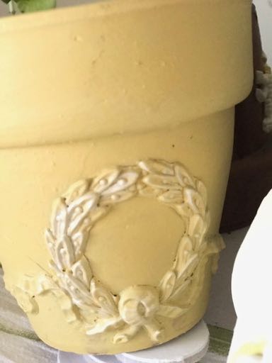 Yellow painted flower pot decorated with a cream B1 laurel wreath and bow Efex flexible moulding