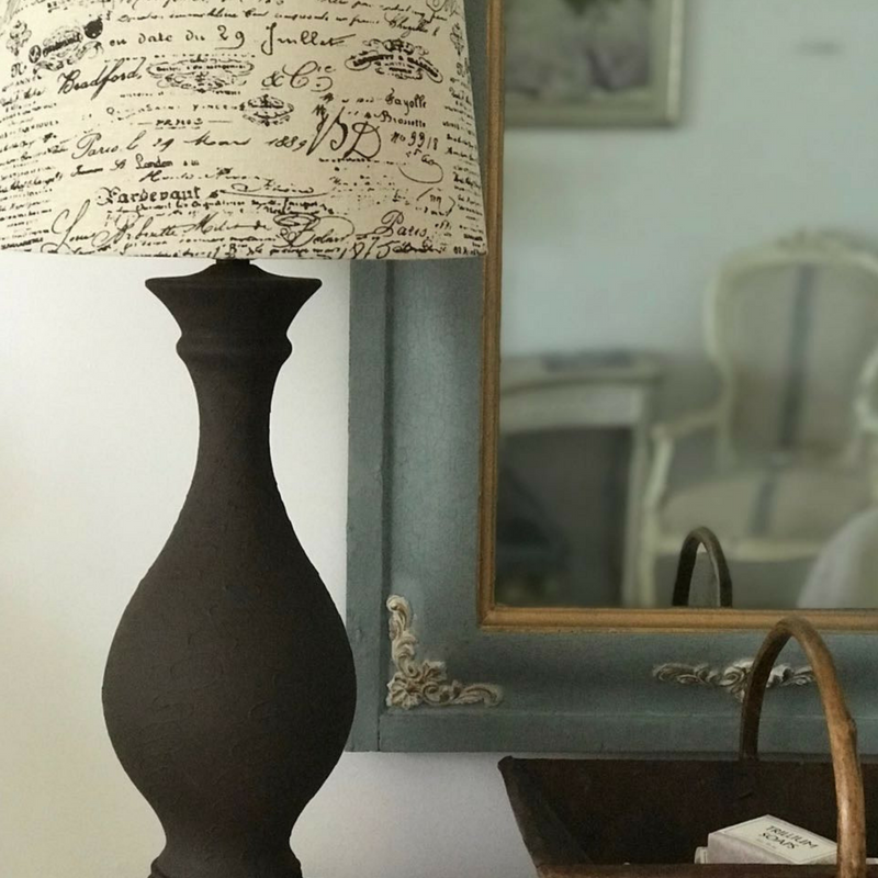 Grey painted mirror frame with C45 French Country Corner Efex flexible mouldings at the corners, behind a dark lamp with a French script shade