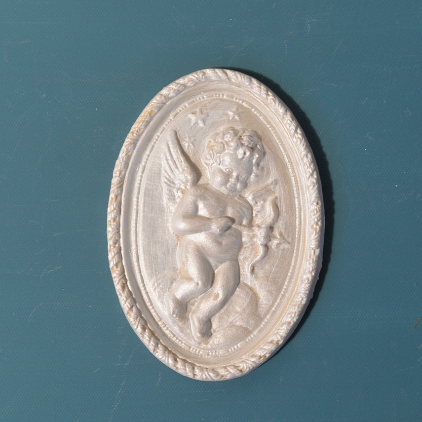 R5 Cherub Rosette, an oval Efex flexible moulding plaque of a winged cherub among clouds and stars inside a rope-twist border