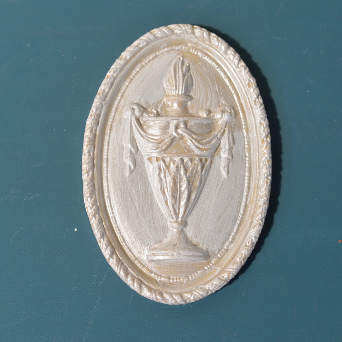 R6 Urn Rosette, an oval Efex flexible moulding plaque with a draped flame-topped urn inside a rope-twist border, pearl finish
