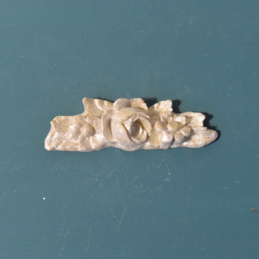 R17 Large Rose Bud Rosette, a horizontal Efex flexible moulding applique of an open rose flanked by buds and leaves, silver-pearl finish
