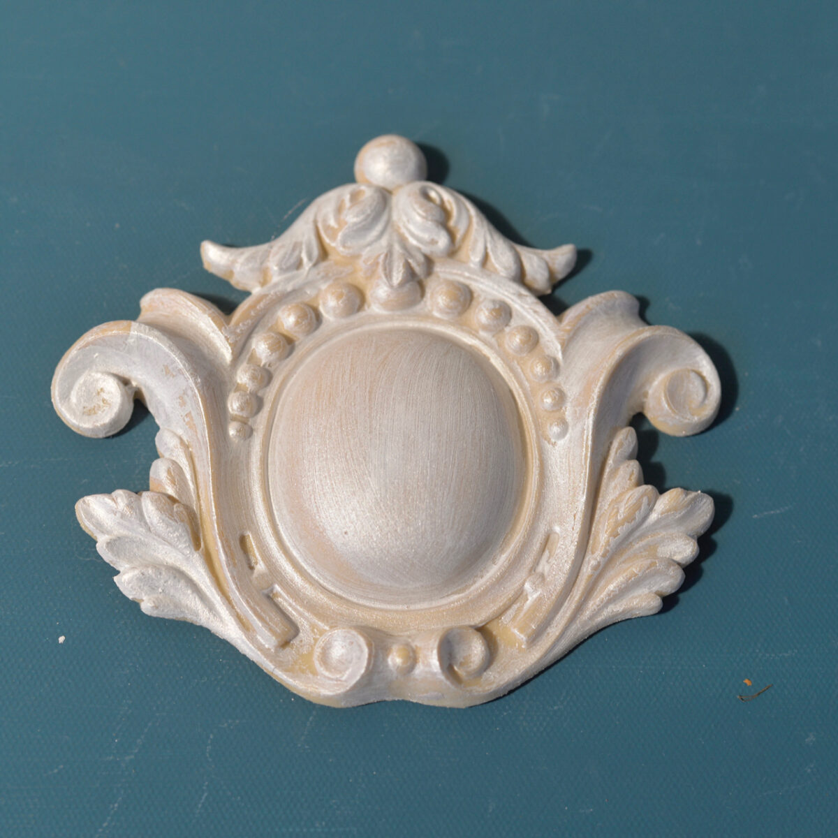 R77 Neoclassic Rosette, an Efex flexible moulding cartouche with a smooth oval centre framed by beads, scrolls and acanthus leaves