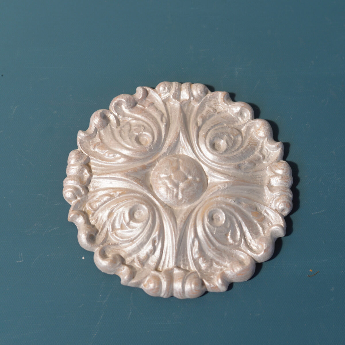 R88 Center Flourish Onlay, a round Efex flexible moulding medallion of swirling acanthus scrolls around a carved centre, pearl finish