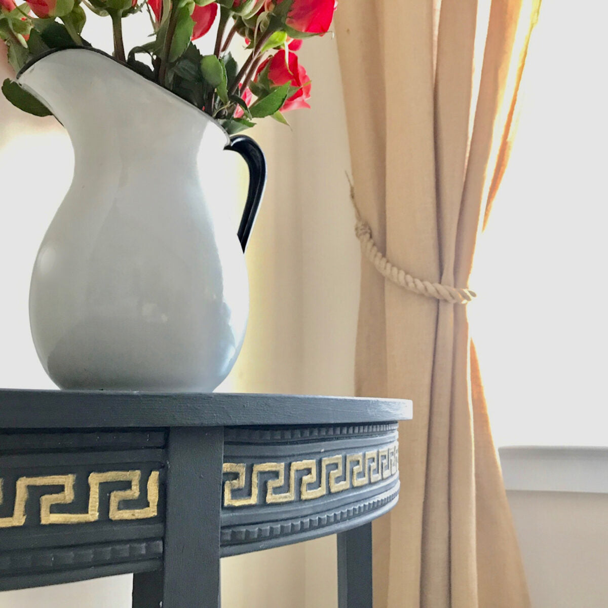Navy painted demilune table with gold-highlighted T33 Greek Key Trim Efex flexible moulding on the apron, beside a white enamel pitcher of red roses