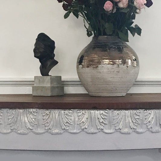 Console table apron finished with T34 Large Acanthus Leaf Efex flexible moulding in white, beneath a bronze bust and a silver vase of pink roses